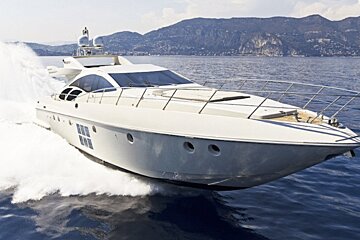 A white yacht is floating in the ocean with mountains in the background
