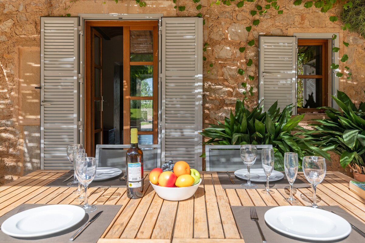 A bottle of wine sits on a table next to a bowl of fruit