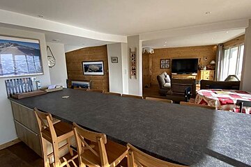 A living room with a table and chairs and a tv