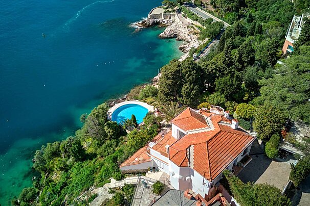 An aerial view of a house on a hill overlooking the ocean