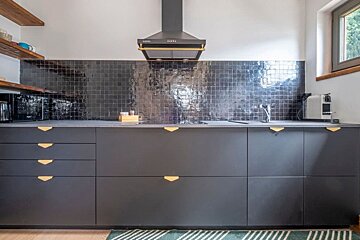 A kitchen with black cabinets and gold handles