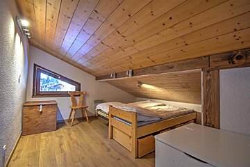 A bedroom with a wooden ceiling and a bed