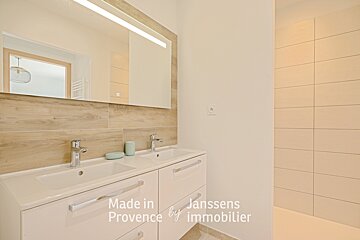 A bathroom with two sinks and a mirror made in provence by immobilier