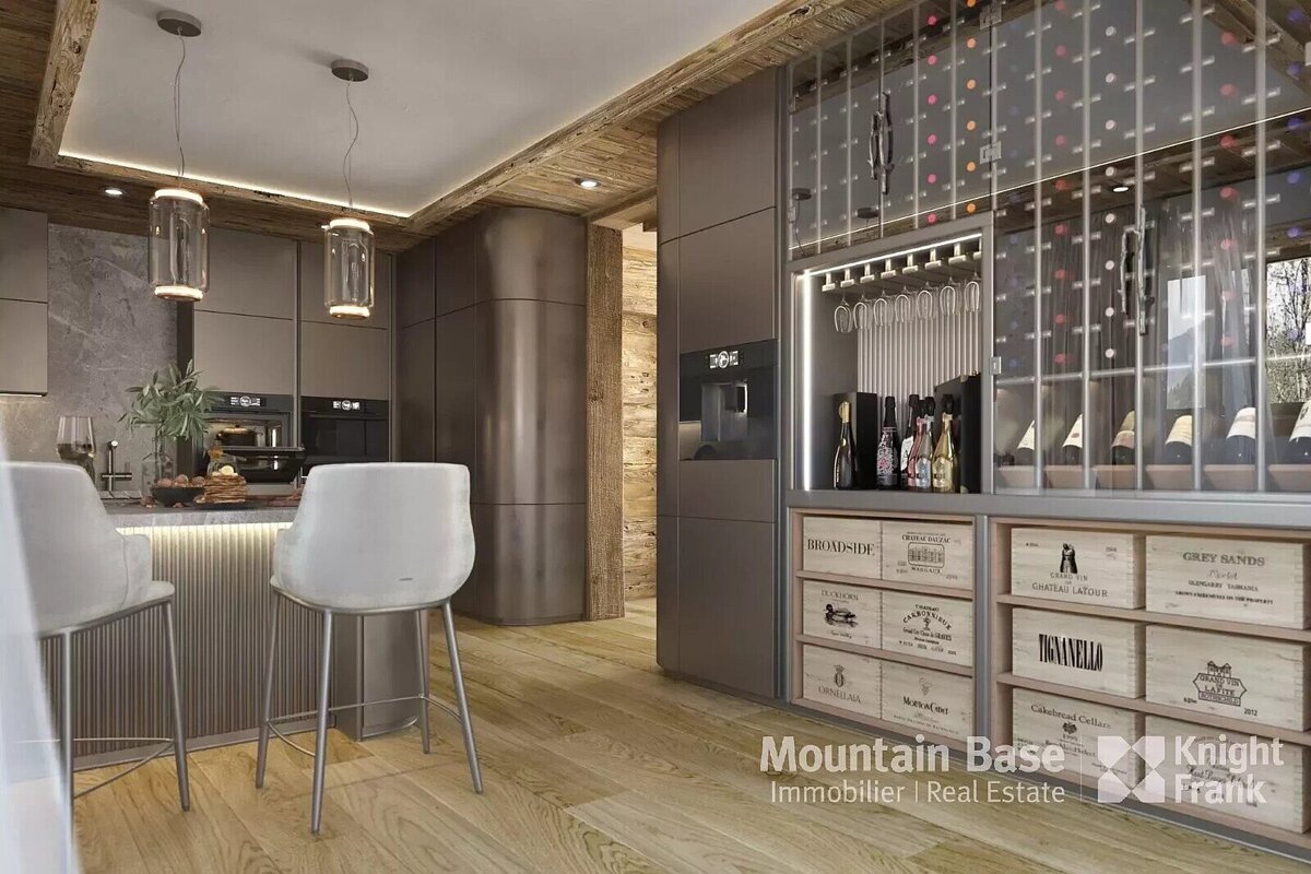 A chic, modern kitchen with dark cabinetry, a breakfast bar, wood accents, and a sophisticated integrated wine storage unit displaying bottles and crates.