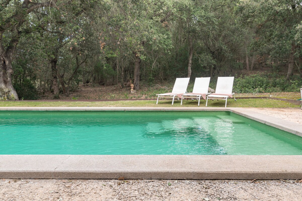 A swimming pool with three white lounge chairs in it