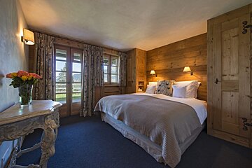 A bedroom with a bed and a table with a vase of flowers on it
