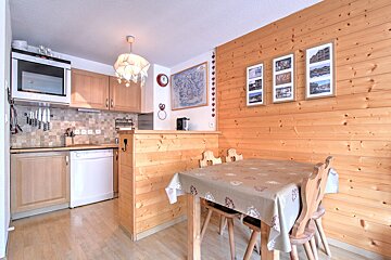 A kitchen with a table and chairs and a clock on the wall