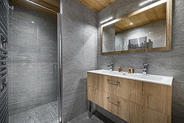 A bathroom with two sinks and a walk in shower