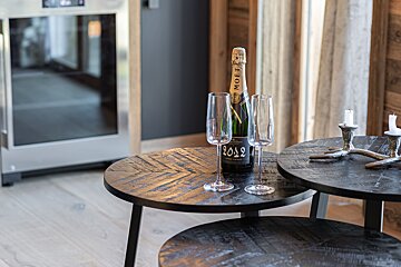 A bottle of Moët champagne and two empty flutes on a dark, nesting wood table.
