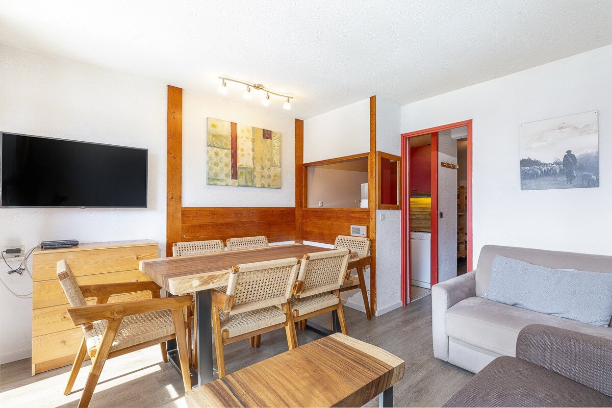 A living room with a table and chairs and a flat screen tv