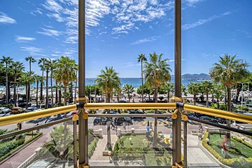 A balcony with a view of the ocean and palm trees