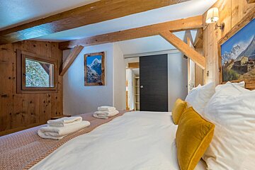 A bedroom with a sliding glass door and a picture of mountains on the wall