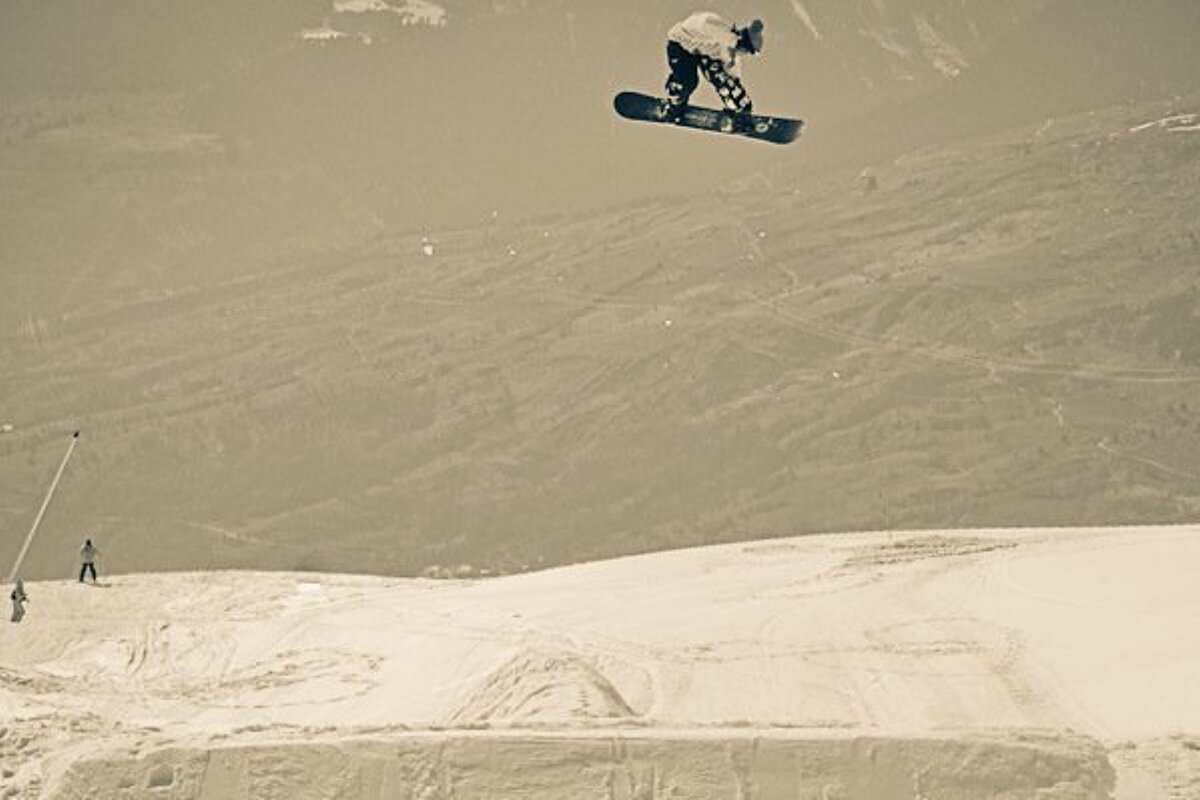 a sepia photo of a snowboarder on a huge jump