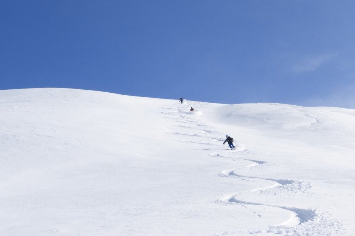 skiers in powder under blue skies in val disere