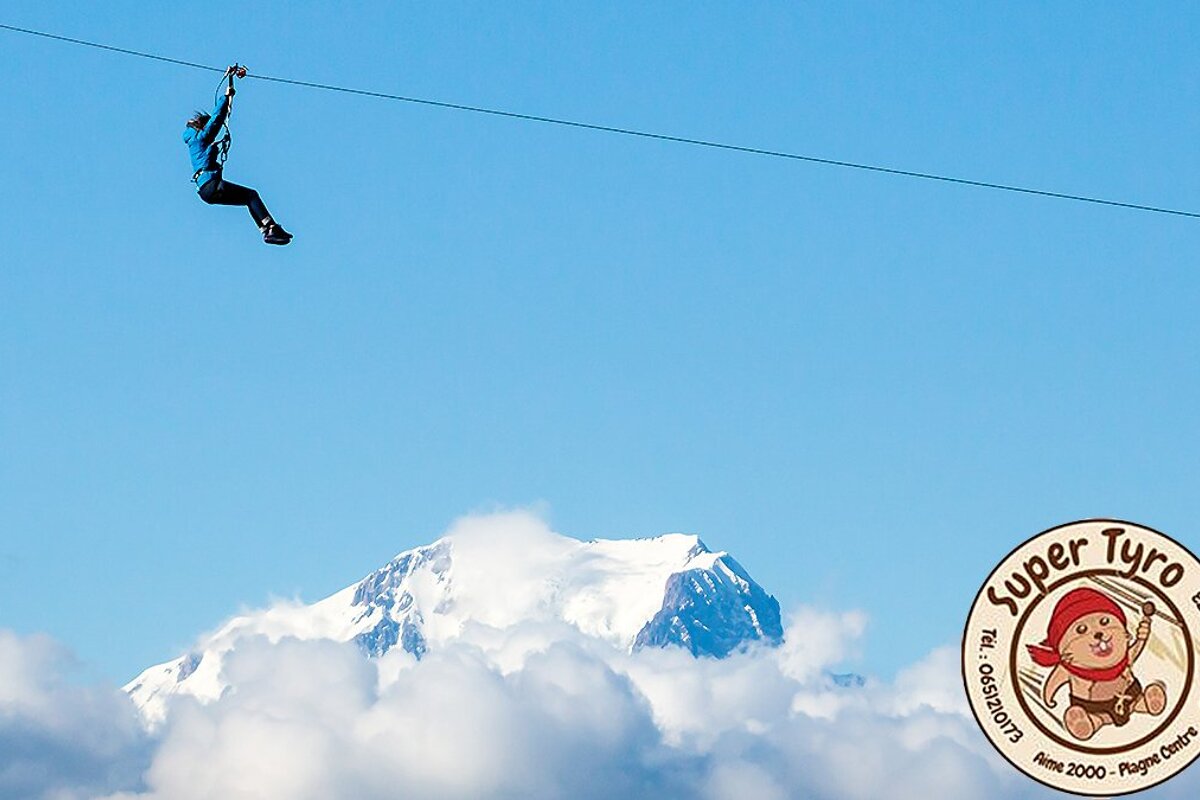 a person on a zipline high about the ski resort of la plagne