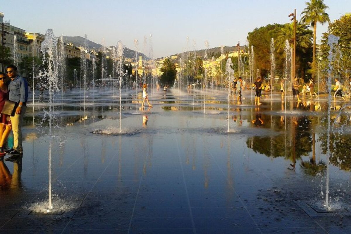 a couple strolling through the fountains of l'miroir d'eua in nice