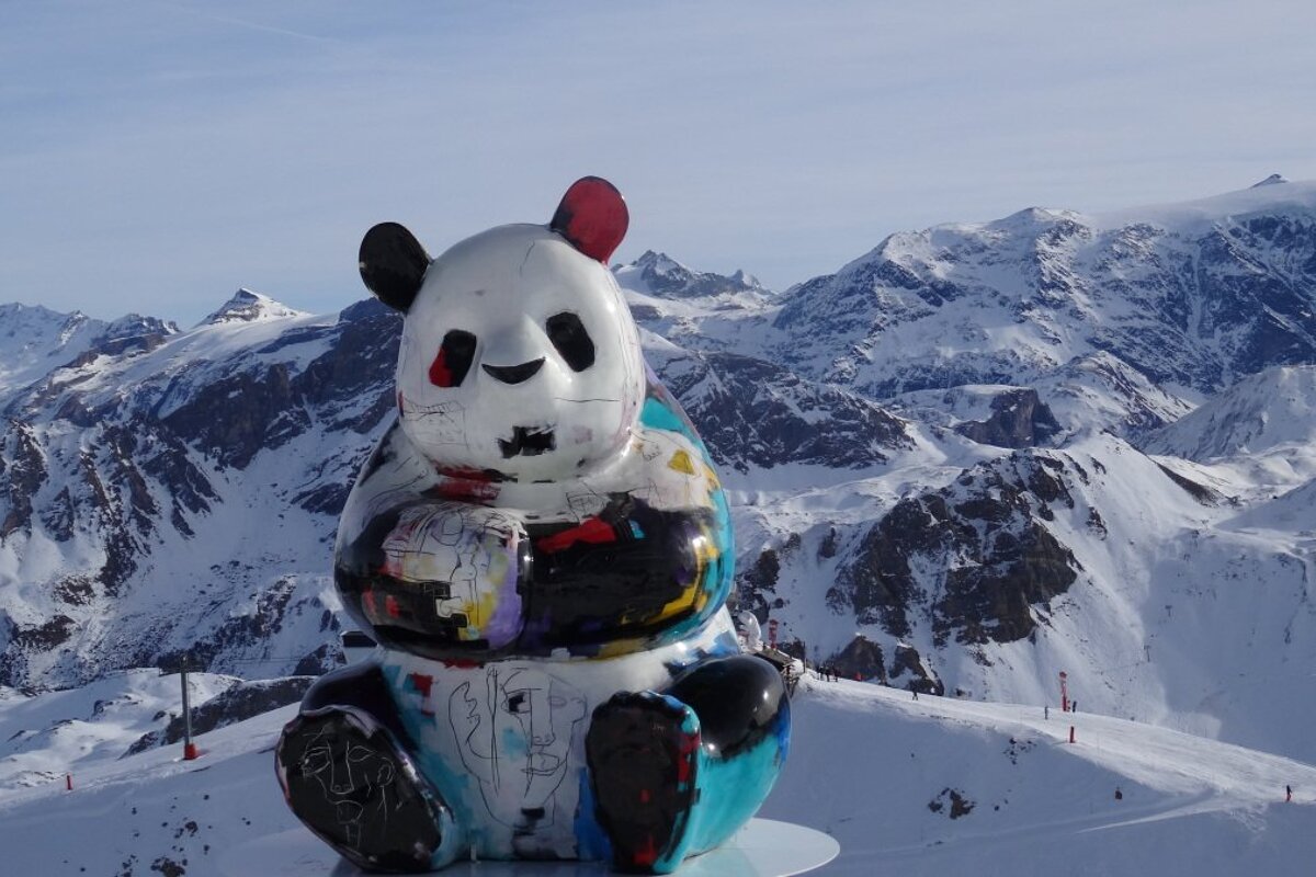 a panda statue in front of snow capped mountains