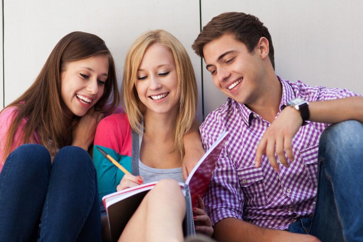 three students looking at a book