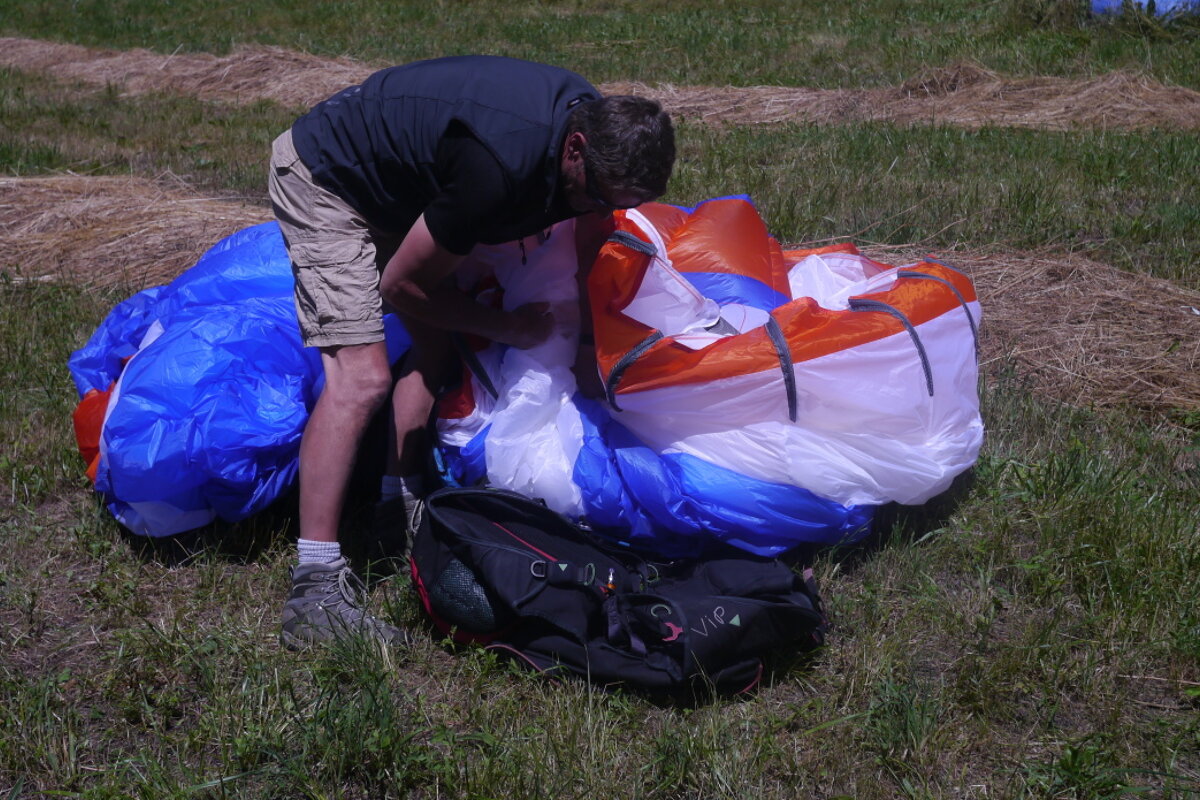a man packing away a parapente wing