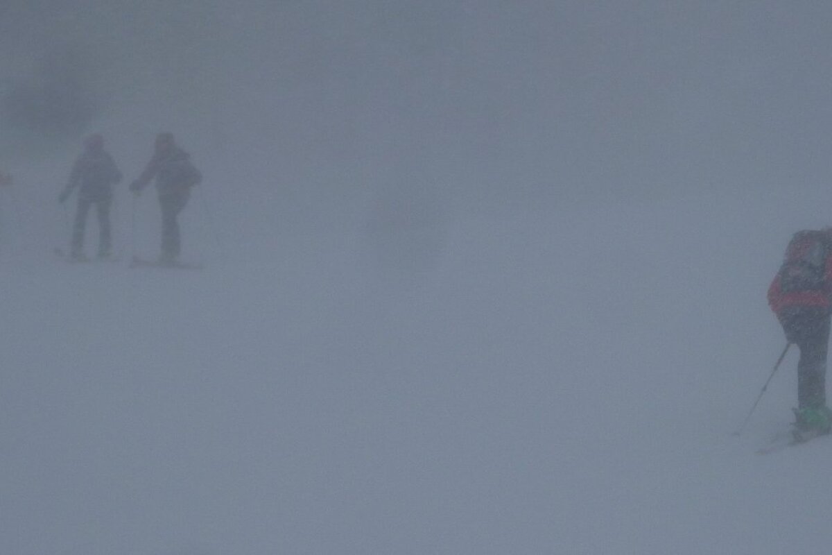 three skiers in fog in val disere
