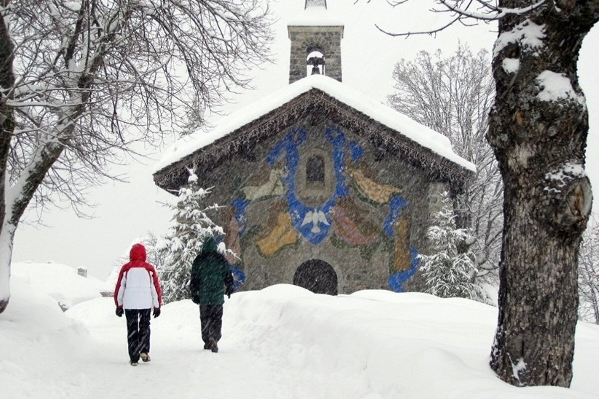 two walkers in the snow going towards a church